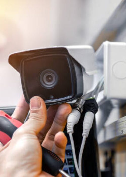 Close-up of surveillance camera installation, male hand holds cctv camera Close-up of surveillance camera installation, male hand holds cctv camera